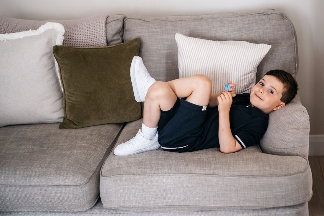 A young boy lying back on the sofa during a family photography session in Derry by Patrick Duddy Photography