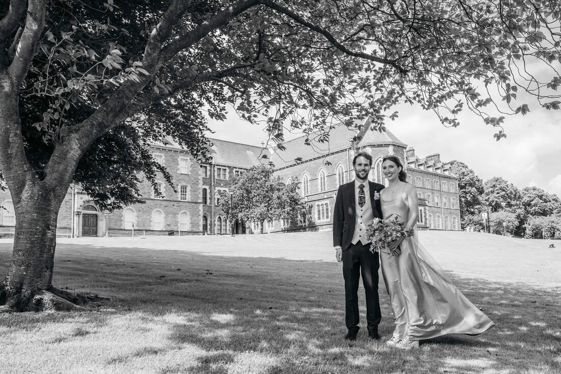 A black and white image of a Derry bride and groom in the grounds of their old school - Lumen Christi College