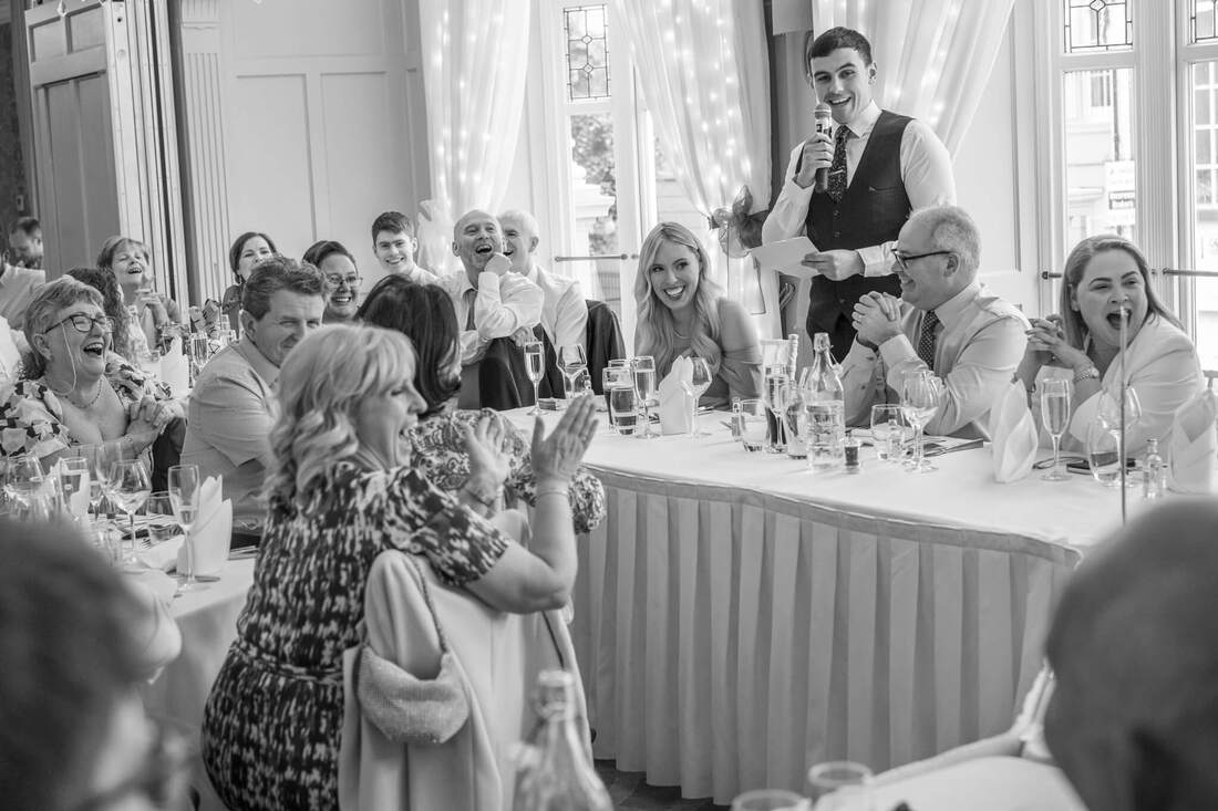Best Man's Speech: A photography of the Best Man delivering a humorous yet touching speech at Bishops Gate Hotel, sharing anecdotes and well-wishes for the Bride and Groom following their Guildhall wedding in Derry.